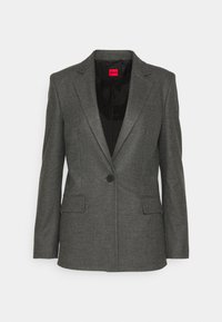 Szary żakiet z teksturowanej tkaniny, z pojedynczym zapięciem na guzik, kołnierzem w typie klap oraz dwiema przednimi kieszeniami. Posiada czarne podszewki z etykietą marki.