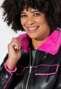 Zwarte leren jas met een fluffy roze kraag en manchetten, zilveren rits en contrasterende roze stiksels op de zakken en naden.