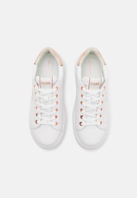 White sneakers with smooth leather upper, round toe, and prominent laces. Features peach accents on heel and eyelets, branded tongue tag.