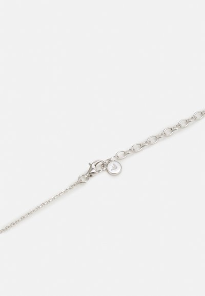 Silver chainarmband med en lobster clasp och en rund berlock med en logo. Länkarna är hoplänkade och rundade, vilket ger en delikat design.