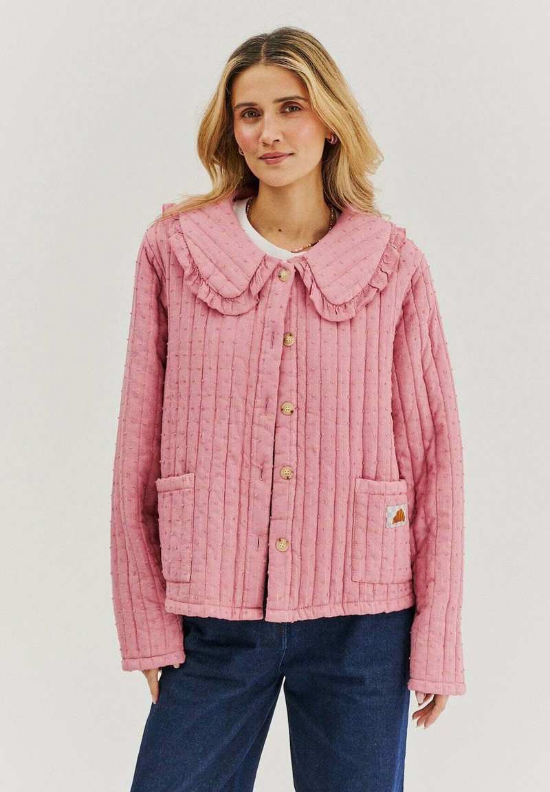 Květovaný růžový kabát s volánovým límcem, s knoflíkovým zapínáním, dvěma našitými kapsami a strukturovanou látkou. Obsahuje malou štítkovou značku na kapse.