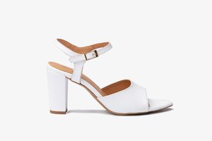 Sandalía blanca de tacón alto con un diseño cruzado, correa ajustable en el tobillo con hebilla y un forro interior beige. Tacón cuadrado.