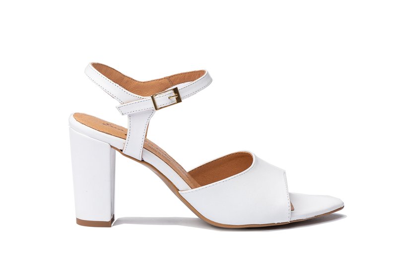 Sandalía blanca de tacón alto con un diseño cruzado, correa ajustable en el tobillo con hebilla y un forro interior beige. Tacón cuadrado.