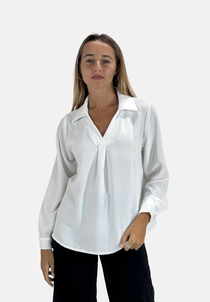 Witte blouse met lange mouwen, V-hals, gestructureerde stof, losse pasvorm en een kleine plooien aan de voorkant. Gecombineerd met donkere broek.