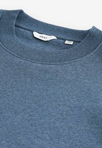 Hanorac albastru cu guler rotund din material cordat. Material moale, textură subtilă, eticheta vizibilă în interiorul gulerului. Design simplu, fără modele suplimentare.