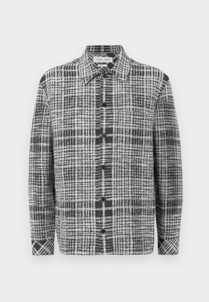 Chemise à carreaux gris et noir avec un devant à boutons, un col pointu et des manches longues en tissu texturé avec des motifs de grille variés.