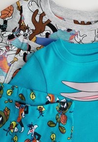 Trzy bluzy: szara z postaciami z kreskówek, jasnoniebieska z dużym wzorem Bugs Bunny oraz turkusowa z animowanymi postaciami.