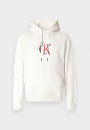 Valkoinen huppari, jossa on etutasku ja rintakehässä punainen ja musta "CK"-logo. Valmistettu pehmeästä kankaasta, jossa on resorit hihansuissa.