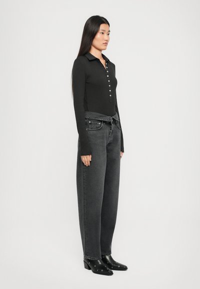 Black long-sleeve top with a collar and button placket, paired with high-waisted gray wide-leg jeans and black heeled ankle boots.