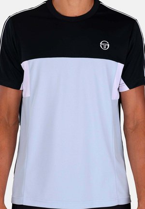 Uomo che indossa una maglietta sportiva a maniche corte bicolore nero e bianco con piccolo logo circolare sul petto sinistro e strisce bianche sulle spalle.