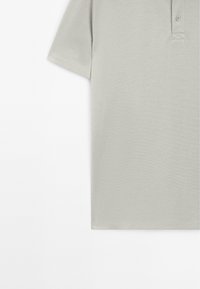 Polo shirt grigio chiaro in tessuto testurizzato, maniche corte, colletto con doppio bottone e vestibilità morbida. Assente di motivi o grafiche.