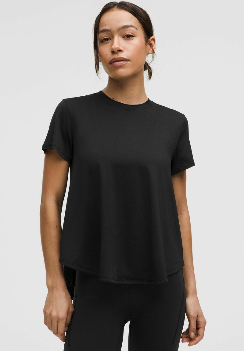 Zwarte T-shirt met korte mouwen, gemaakt van zacht materiaal, met een klassiek ronde halslijn, minimaal ontwerp en een comfortabele pasvorm die iets uitloopt bij de zoom.
