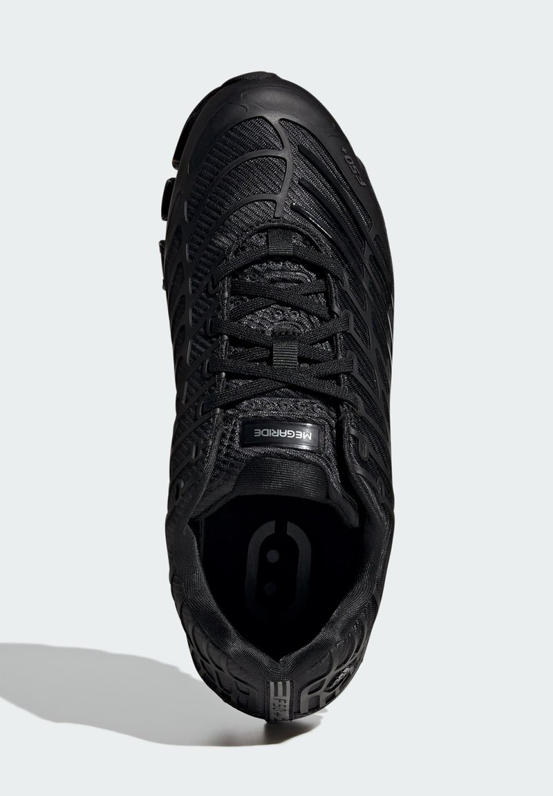 Chaussure de sport noire avec une tige texturée, des lacets fins et une semelle extérieure en caoutchouc. Présente un design épuré et un logo circulaire sur la semelle intérieure.