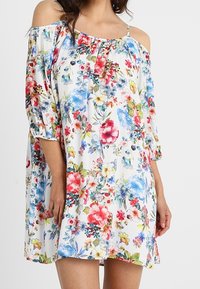 Květinové šaty s odhalenými rameny, vícerozměrnými vzory, lehkým materiálem a volným střihem, s kulatým výstřihem a střední délkou.