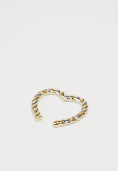 Iškreiptas metalinis žiedas su besikeičiančiomis auksinėmis ir sidabrinėmis tonacijomis, atviras dizainas, lygus paviršius ir suapvalinti galai.