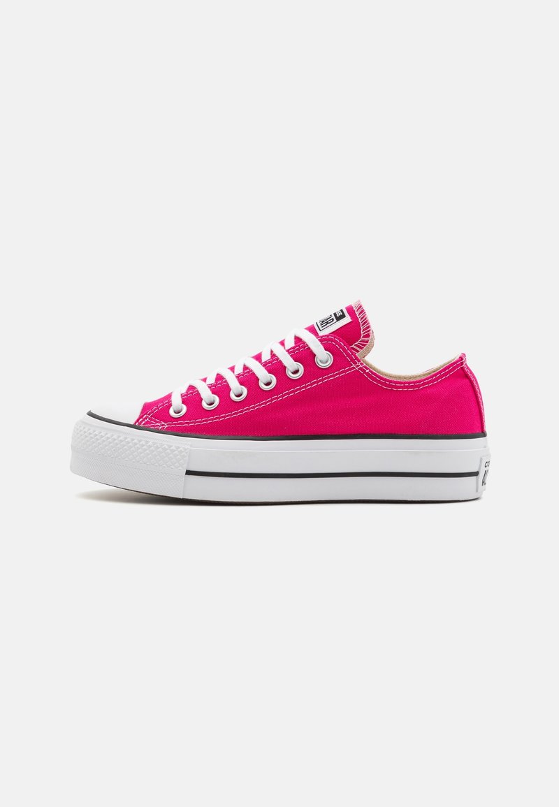 Sneakers in tela rosa con lacci bianchi, punta in gomma e striscia nera sulla suola. Presentano un design a scarpa bassa.