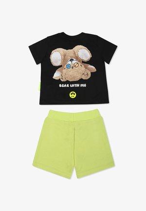 Sort bomulds t-shirt med et plysbjørn grafik og blå og orange knapper, parret med lysegrønne bomulds shorts.