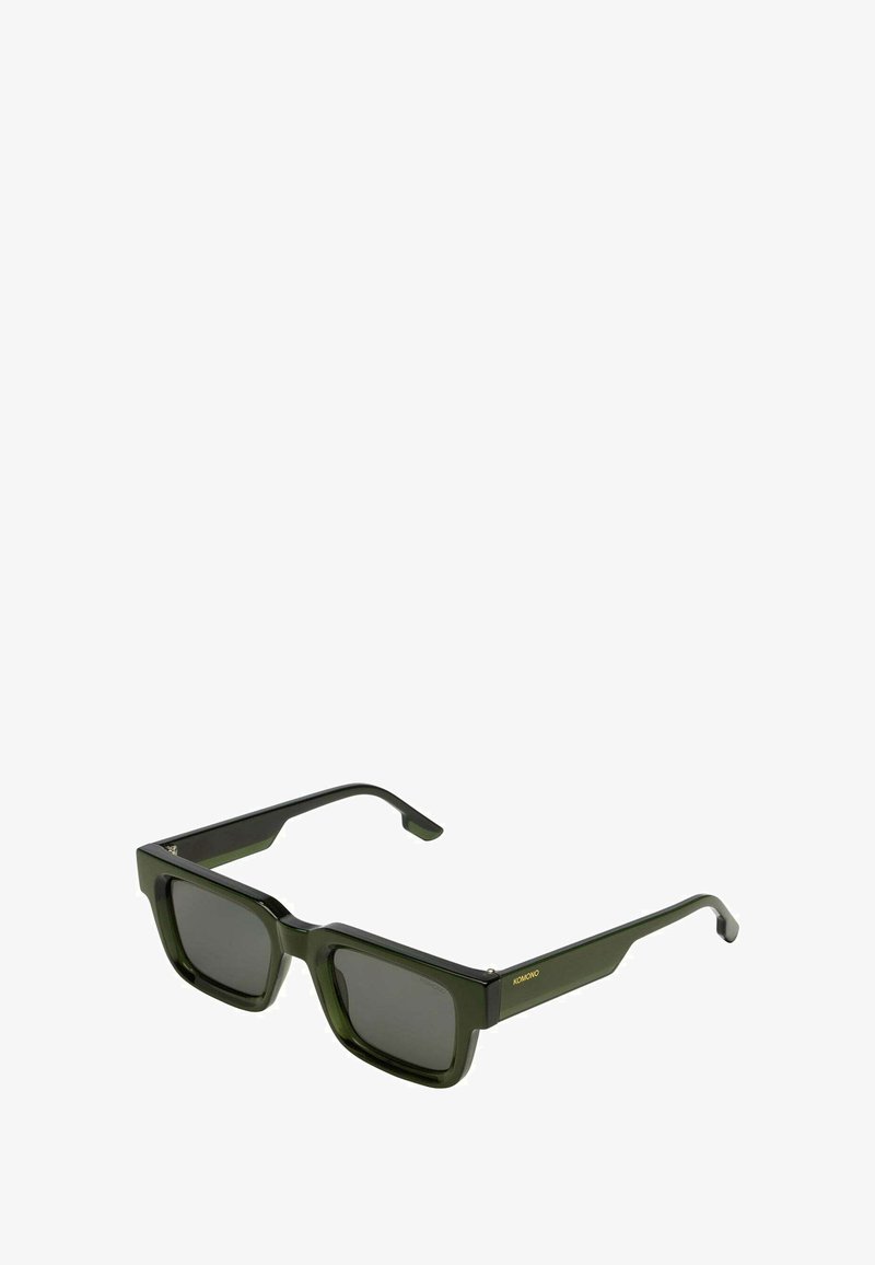 Vierkante groene zonnebril met donkere glazen, een dik kunststof frame en een gouden logo-accent aan de zijkant. Strak, modern ontwerp.