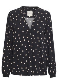 Blouse noire à manches longues avec des pois beiges, encolure en V et léger pli à l'avant.