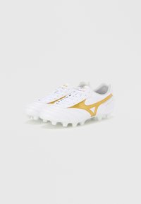 White soccer cleats with a yellow accent, smooth texture, laced design, and distinct studs on the outsole for traction.