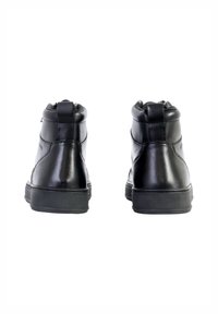 Bottines en cuir noir avec une texture lisse, bout rond et fermeture éclair sur le côté. Caractéristiques d'une semelle en caoutchouc et de détails de couture.