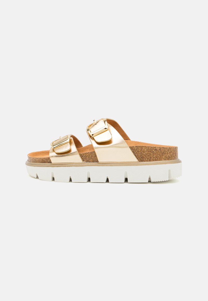 Metallic gold slide sandals with two adjustable buckles, cork footbed, and white textured sole. Side view highlights layered materials.