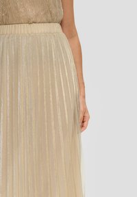 Jupe beige plissée avec des rayures verticales brillantes, dotée d'une large taille et d'une texture douce et fluide. Le tissu a un effet léger et scintillant.