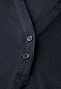 Marineblaue Baumwollbluse mit V-Ausschnitt, zwei schwarzen Knöpfen und glatter Textur. Gerade Saumlinie und kurze Ärmel.