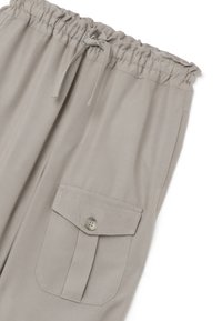 Pantalones cargo beige hechos de una tela suave, que cuentan con una cintura ajustable con cordón, bolsillos laterales y un gran bolsillo con solapa y detalle de botón.