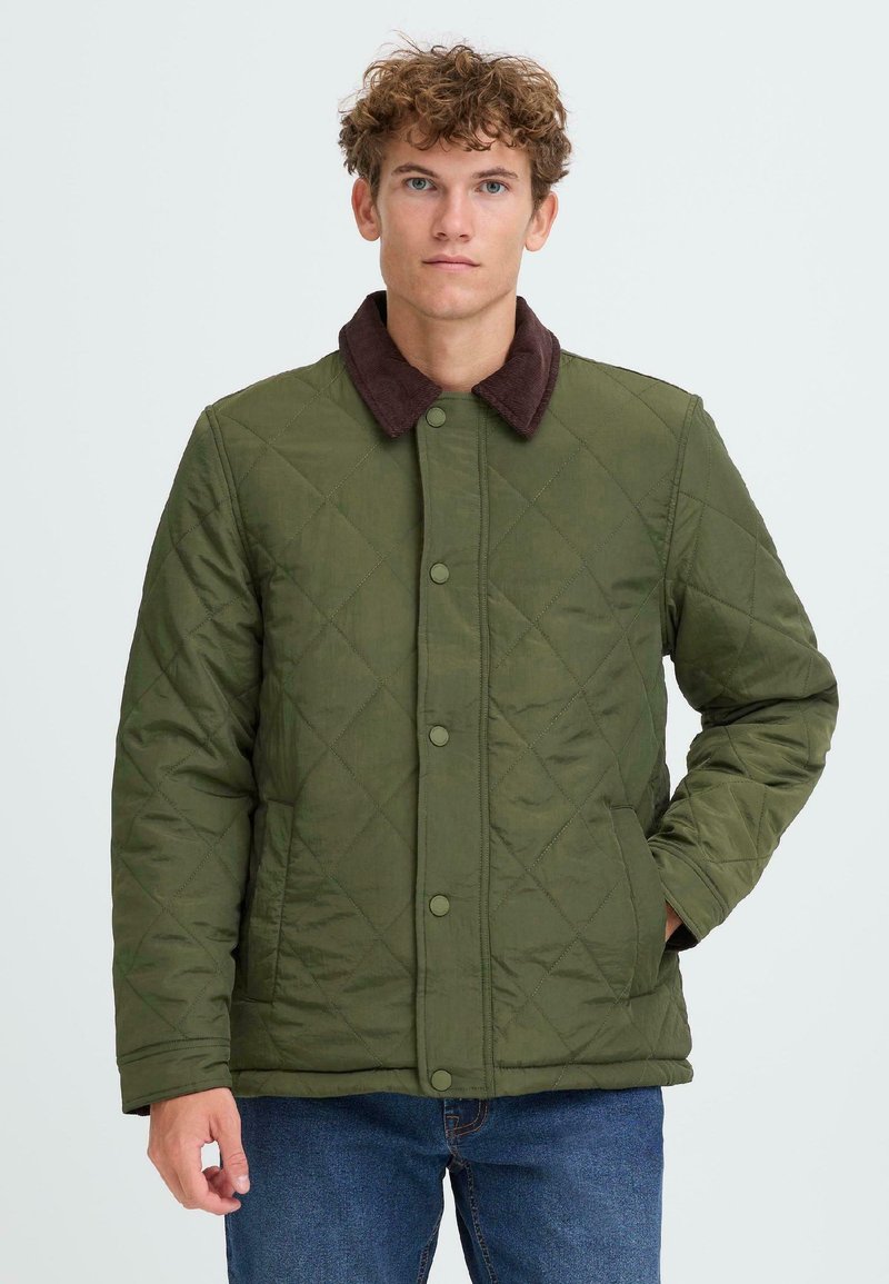 Giacca trapuntata verde con collo in corduroy marrone, chiusura frontale con bottoni a pressione e tasche laterali. Adatta per un abbigliamento casual.