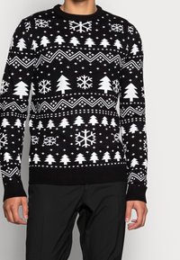 Svart stickad tröja med vita mönster av träd, snöflingor och geometriska former. Rund halsringning och ribbade ärmslut och nederkant.