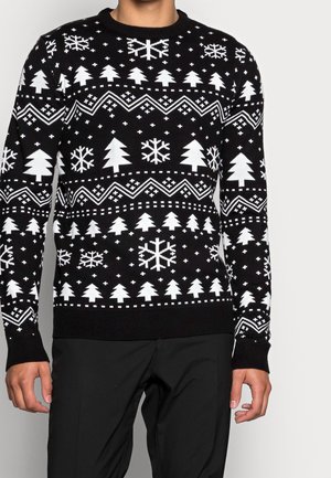 Pull en maille noir avec des motifs blancs d'arbres, de flocons de neige et de formes géométriques. Col rond et poignets et ourlet côtelés.