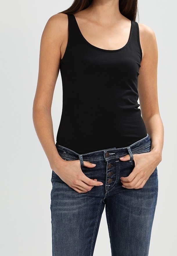 Svart ärmlös top i mjukt material, kombinerad med blå denimjeans med hög knappstängning och avslappnad passform.