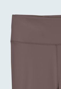 Leggings marron taille haute présentant une texture lisse et des coutures plates, avec un design ajusté pour le confort et la liberté de mouvement.