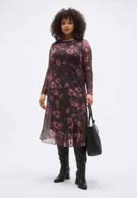 Rochie cu mâneci lungi, din material transparent cu model floral, pe fond închis și flori roz, prevăzută cu tiv fluid. Asortată cu cizme negre din piele, până la genunchi, și o geantă.