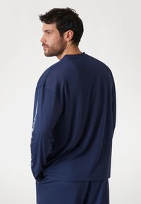 Marineblauwe longsleeve shirt van textuurstof, met een ronde hals en een relaxte pasvorm met subtiele zijventilatie aan de onderkant.