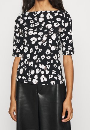 Top de manga corta con estampado floral en blanco y negro, combinado con falda de cuero negra, visto desde los hombros hasta la mitad del muslo.