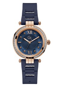 Orologio rotondo con cinturino in gomma blu e dettagli in oro rosa. Presenta un quadrante blu testurizzato, numeri romani alle posizioni 12 e 6, e hardware argentato.