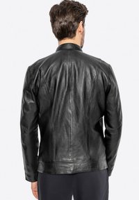 Giacca in pelle nera con un design aderente, texture liscia e cuciture strutturate. Presenta un colletto classico e maniche lunghe.