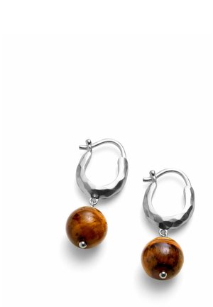 Srebrne kolczyki-koła z młotkowaną fakturą, każdy z zawieszką w postaci okrągłej brązowej drewnianej perły wiszącej poniżej koła.