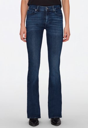 Uitlopende donkerblauwe jeans met een soepele textuur, vijf-pocket ontwerp en subtiele stiksels. Ceintuurlussen en metalen knoopsluiting.