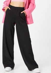 Svarta randiga vida byxor med hög midja, sidofickor och en slät tygfinish, ihop med en rosa blazer.