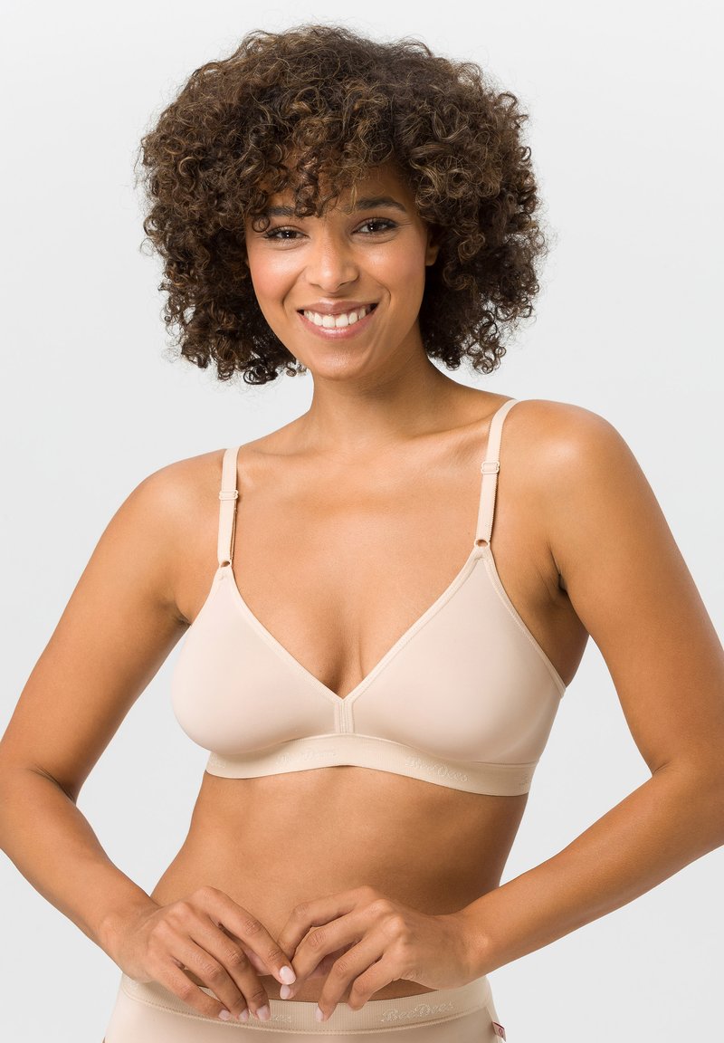 Beige kabelloser BH mit dreieckigem Design, weichem Stoff, verstellbaren Trägern und breitem Unterband für Unterstützung. Glatte Textur, minimale Details.