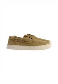 Zapatos de lona de color marrón claro con una textura suave, con suelas de goma blanca, cordones redondos y detalles de ojetes a los lados.