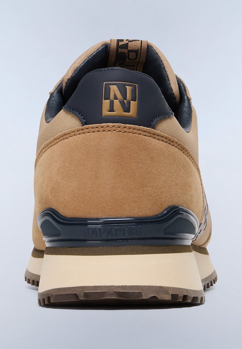 Zapatillas de ante marrón con forma redondeada, detalles en cuero azul marino y una suela texturizada con la marca "NAPAPIURI" en el talón.