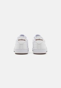 Bijele Reebok tenisice s glatkom kožnom površinom, s smeškastim logotipom, niskim dizajnom i teksturiranim gumenim đonovima.
