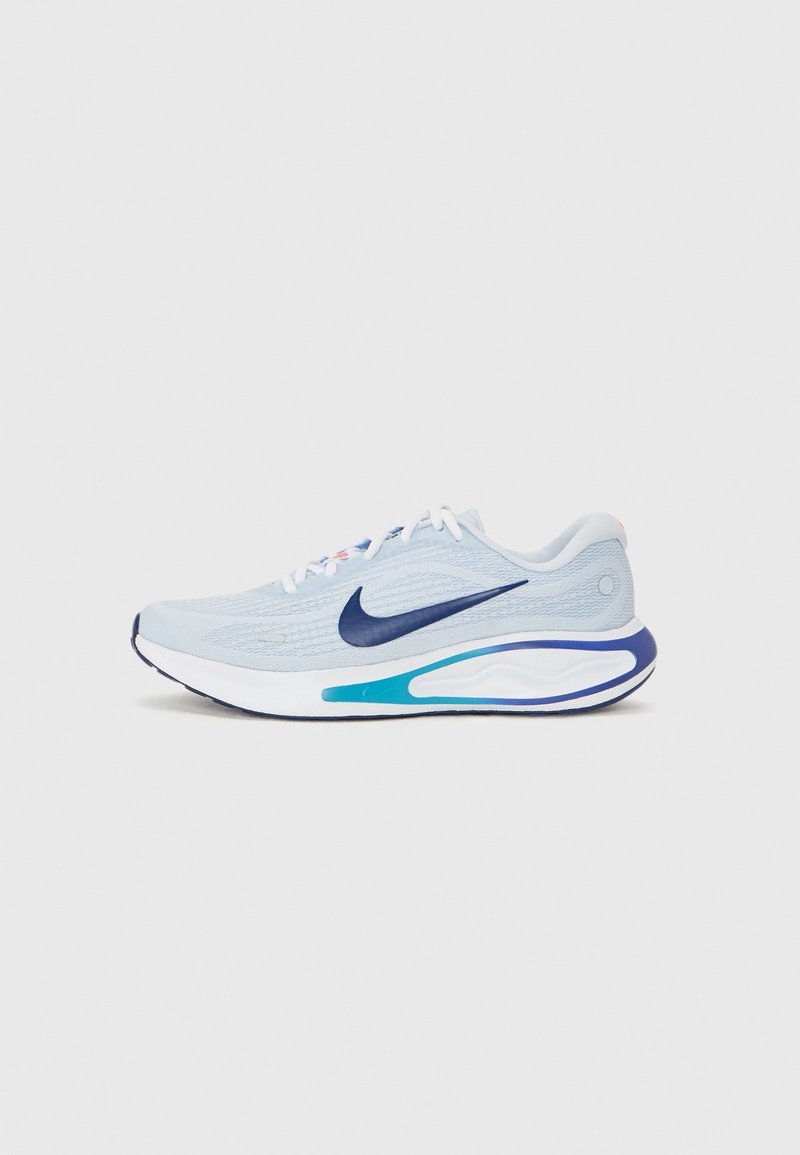 Light blue running shoe with a textured upper, navy swoosh logo, padded collar, white laces, and a multicolored sole with blue accents.