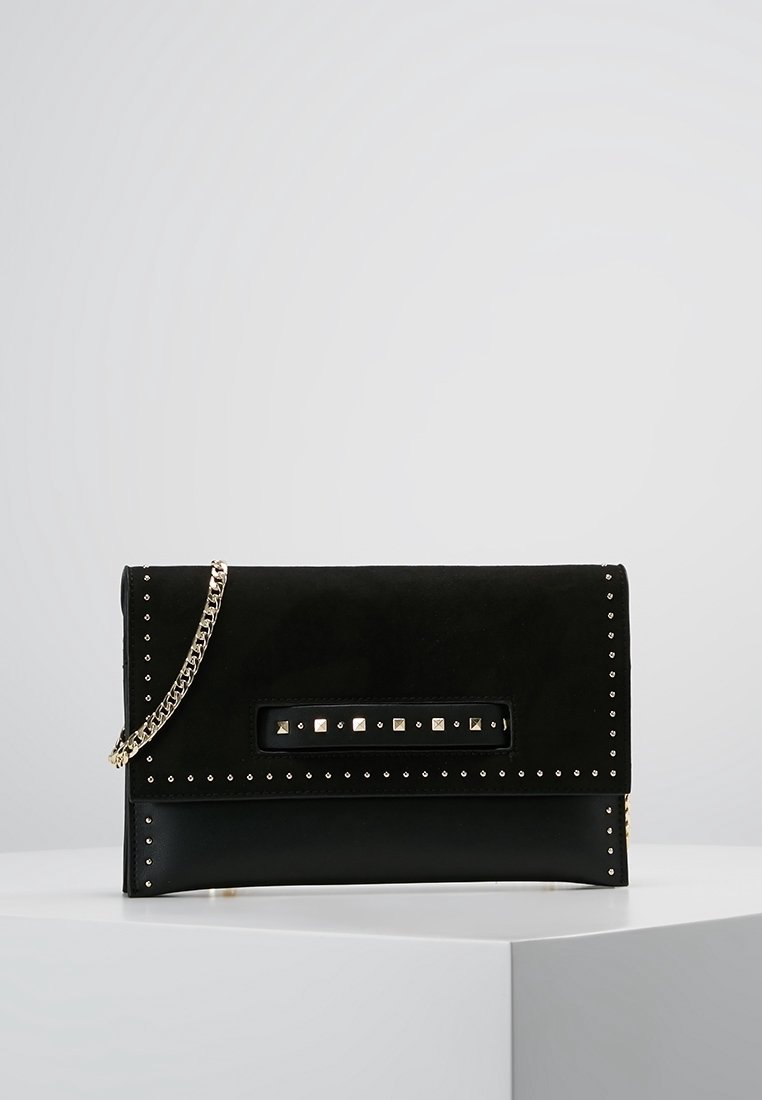 Zwarte suède clutch tas met zilveren studs op de randen, rechthoekige vorm, plat ontwerp, voorzien van een kettingriem en een decoratief metalen plaatje.