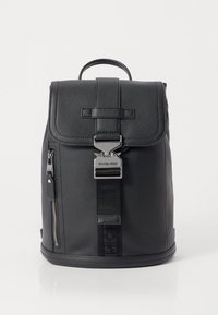 Black leather backpack with a textured finish, flap closure, zippered side pocket, and metallic hardware featuring the brand name.