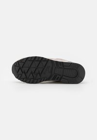 Sneaker chiaro con tomaia grigia testurizzata, suola in gomma nera con un motivo di battistrada robusto e logo del marchio discreto sul lato.